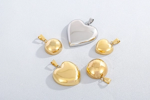 Polished silver heart pendant and gold dome earrings jewelry set on textured white surface
