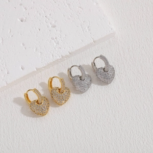 Detail of heart hoop earrings in gold and silver finish with pavé set cubic zirconia