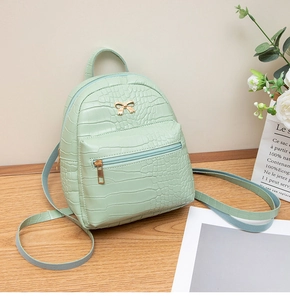 Detail of light green crocodile pattern mini backpack with golden bow accent