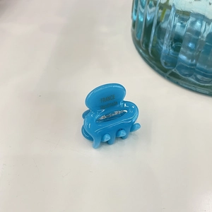Detail of blue acetate hair claw clip showing the FRANCE Handmade text on white surface