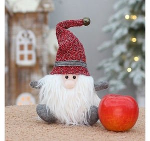 Detail of Christmas gnome gift bag with red knit hat and white beard beside a red apple