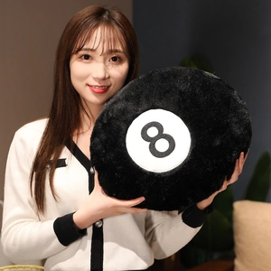 Detail showing plush black No. 8 billiard ball pillow held by a model for size display