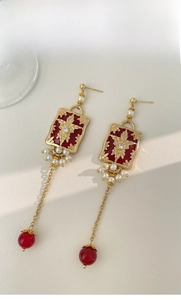 Detail view of vintage gold tassel earrings with red enamel flowers and white pearls