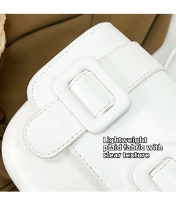 Detail of white leather saddle bag showing precise stitching and square buckle texture