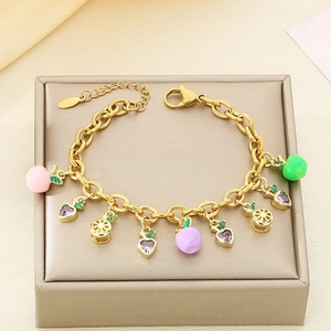 Detail of gold-plated stainless steel bracelet with colorful fruit zircon charms on jewelry box