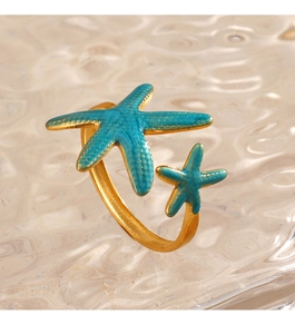Macro detail of 18K gold starfish rings with teal enamel finish on water rippled glass