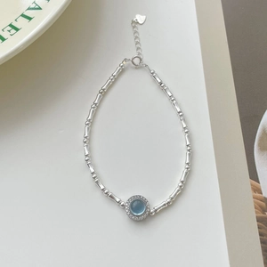 Macro view of S925 sterling silver bamboo chain bracelet with blue stone and heart tag