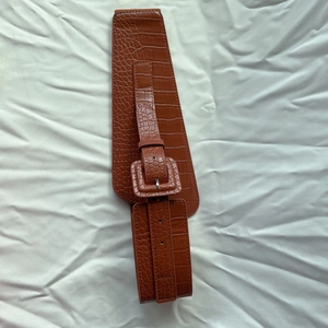 Close-up of brown crocodile pattern wide elastic belt with large square buckle detail