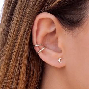 Detail of golden moon stud and ear cuffs set worn on ear for minimalist styling