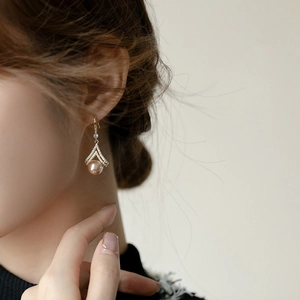 Elegant champagne pearl earrings with gold V-shaped diamond accents worn by a model