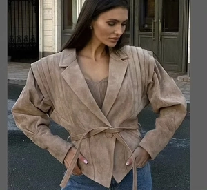 Détail d'une veste en daim beige avec épaules bouffantes et ceinture assortie
