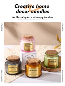 Detail of four colored glass scented candles with cork stoppers and gold labels on tray