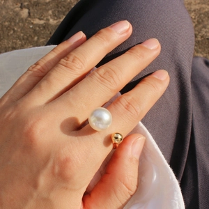 Detail of elegant U-shaped open ring featuring a white pearl and gold bead on hand