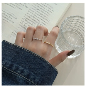 Close-up of a silver bow ring with micro-set zircons worn on a finger over a book