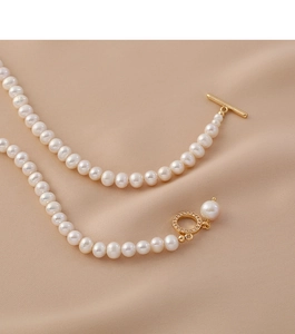 Detailed close-up of natural freshwater pearls with a gold OT toggle clasp on beige fabric
