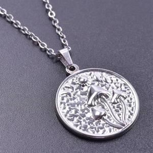 Macro shot of a silver sun, moon, and mushroom embossed circular coin pendant on a chain