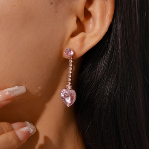 Detail of pink heart-shaped zircon drop earring worn by model with sparkling tassels