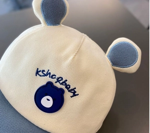 Détail de la casquette bébé avec écusson ours et broderie kshopbaby sur le devant