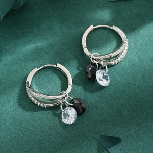 Silver drop earrings with sparkling rhinestones and black zircon charms on green background