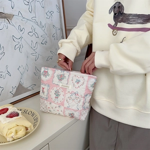 Close-up of quilted floral makeup bag featuring pink gingham fabric and a small bow