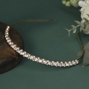 Close-up of a golden bridal headband with white rhinestones on a vintage wooden base