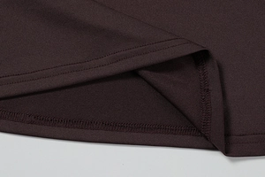Macro detail of the dark coffee knit dress hem showing precise stitching and fabric texture