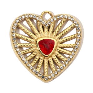 Macro shot of gold heart pendant with red triangular gem and sparkling rhinestones