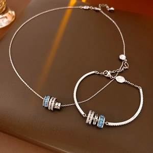Macro shot of silver necklace and bracelet set with blue stones and zircon pavé charms