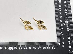 Macro detail of leaf-shaped stainless steel earrings with gold plating and size measurements