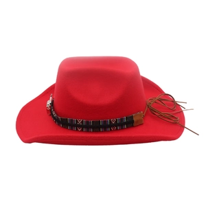 Close-up of a red ethnic Western cowboy hat featuring a tribal band and bull head charm.