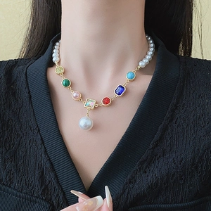 Macro shot of colorful gemstone stitching and lustrous white pearls on a gold necklace