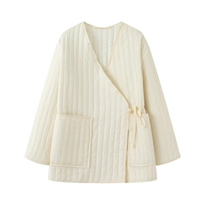 Detail of cream quilted cotton jacket featuring V-neck and tie-side closure design