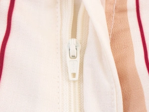 Gros plan détaillé de la fermeture éclair YKK blanche sur tissu à rayures multicolores