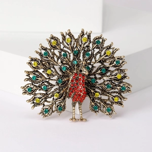 Close-up of vintage gold peacock brooch with vibrant green and yellow rhinestones
