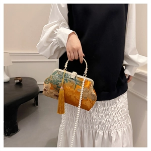 Detail of retro floral handbag with golden handle, pearl chain, and yellow tassel accent