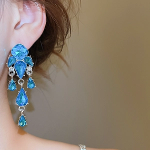 Primo piano di orecchini pendenti in argento con cristalli blu su una modella