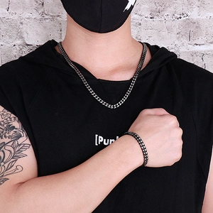 Close-up of stainless steel Cuban link necklace and bracelet set on a streetwear model