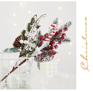 Detail of snowy Christmas pine branch with pinecones, red berries, and plaid fabric bow