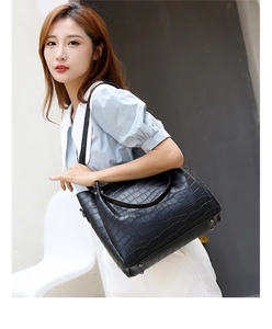 Detail of black faux crocodile leather tote bag with sturdy top handles and shoulder strap