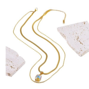 Double-layered gold necklace with square iridescent pendant and snake chain on white stone
