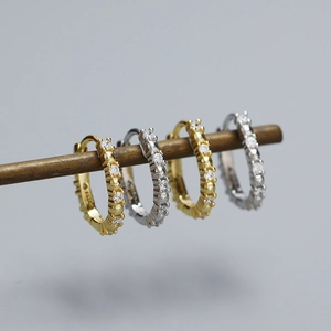Close-up of S925 sterling silver huggie earrings with CZ stones on vintage wood stand