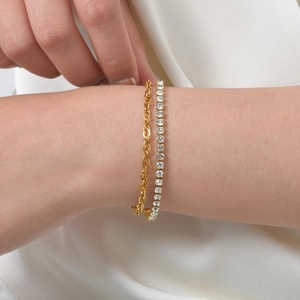 Close-up of stacked gold rope chain and silver tennis bracelet with green zircon