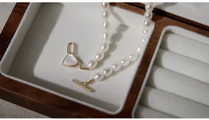 Close-up of freshwater pearl necklace with golden heart pendant in a luxury wooden box