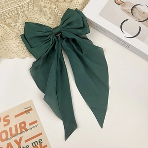 Detail shot of the dark green oversized bow hair clip with flowing chiffon ribbons