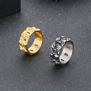 Close-up of gold and silver skull rings featuring detailed 3D gothic relief engraving
