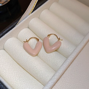 Detailed macro view of pink enamel heart-shaped earrings with gold plating and fine polish