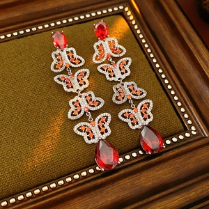 Détail macro de boucles d'oreilles papillon vintage avec gemmes rouges et zircons oranges