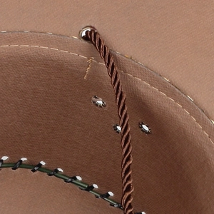 Detail of western straw hat featuring brown twisted drawstring and metal eyelet
