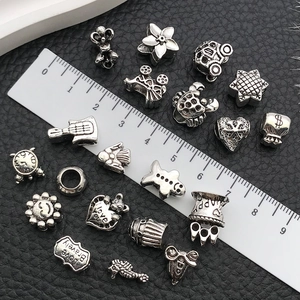Silver vintage alloy beads in heart and crown shapes on black leather background