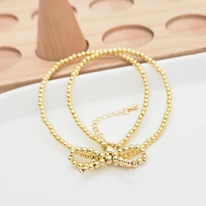 Dettaglio di un bracciale a perline placcato oro 18K con fiocco su supporto espositivo